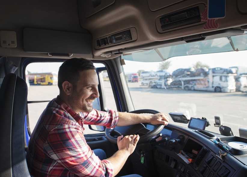 Professional truck driver with smile driving truck and delivering goods on time.